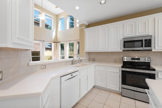 kitchen with light tile patterned flooring, white cabinetry, sink, hanging light fixtures, and stainless steel appliances