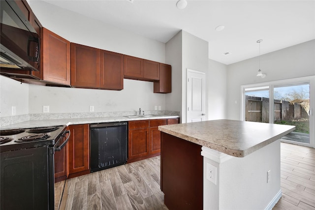 kitchen with sink, hanging light fixtures, a center island, black appliances, and light wood-type flooring
