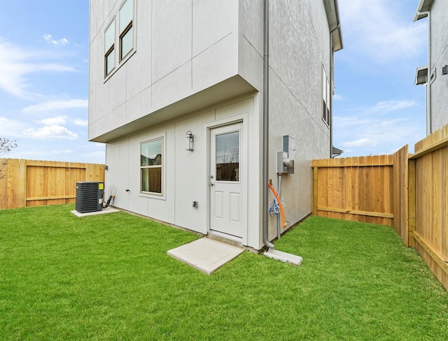 rear view of house with central AC and a lawn