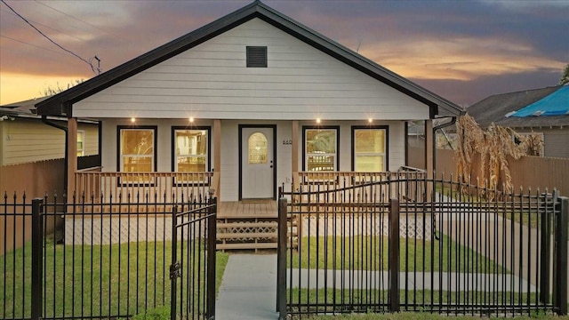 bungalow-style house with a fenced front yard, covered porch, a front lawn, and a gate