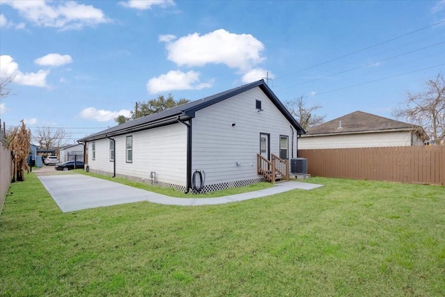 6609 Ave Q, Houston, TX 77011 - rear view of house with a lawn, entry steps, roof mounted solar panels, central AC, and fence