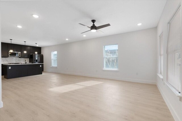6609 Ave Q, Houston, TX 77011 - unfurnished living room featuring a healthy amount of sunlight, light wood-style flooring, and baseboards