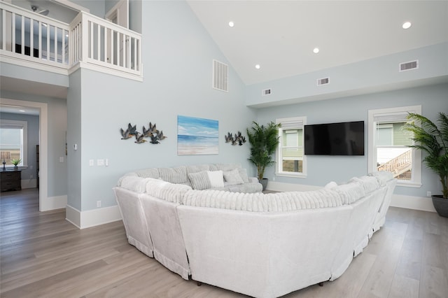 living room with high vaulted ceiling and light wood-type flooring