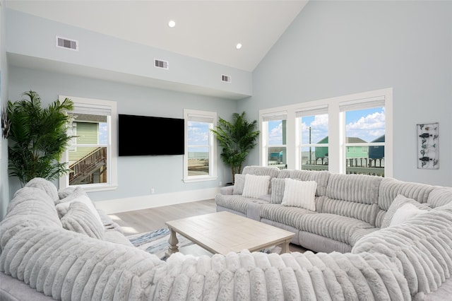 living room featuring high vaulted ceiling and light hardwood / wood-style floors