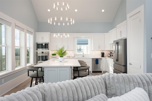 kitchen with white cabinetry, stainless steel appliances, a breakfast bar, and a kitchen island