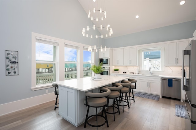 kitchen featuring stainless steel appliances, a kitchen island, hanging light fixtures, and white cabinets