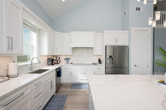 kitchen featuring sink, white cabinetry, tasteful backsplash, light stone counters, and appliances with stainless steel finishes