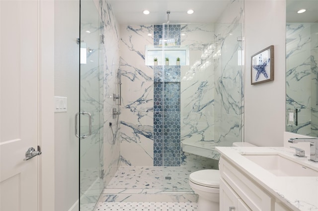 bathroom with vanity, a shower with door, and toilet