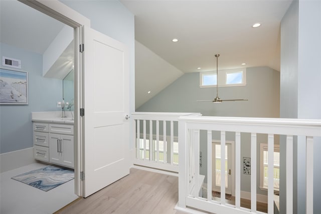 hall with vaulted ceiling and light hardwood / wood-style floors