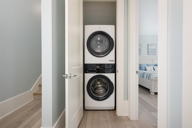 laundry room featuring light hardwood / wood-style flooring and stacked washing maching and dryer