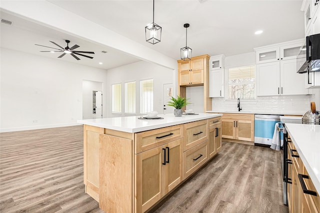 kitchen featuring hardwood / wood-style floors, a center island, stainless steel dishwasher, and decorative light fixtures