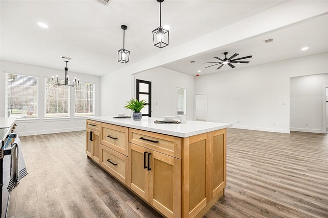 kitchen featuring pendant lighting, hardwood / wood-style flooring, ceiling fan with notable chandelier, and a kitchen island