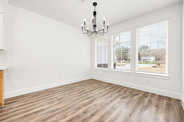 unfurnished dining area featuring a notable chandelier and hardwood / wood-style flooring