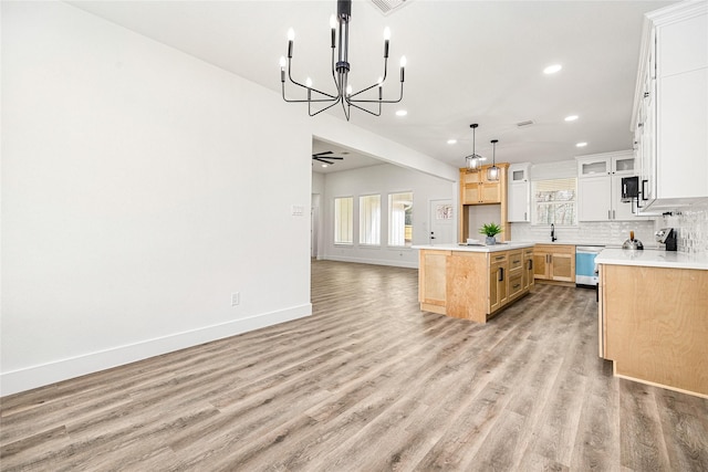 kitchen featuring dishwasher, a kitchen island, white cabinets, hardwood / wood-style floors, and backsplash