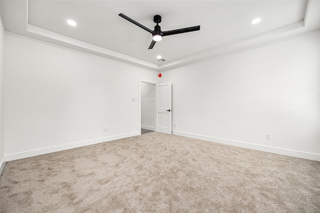 spare room featuring a tray ceiling, ceiling fan, and carpet flooring