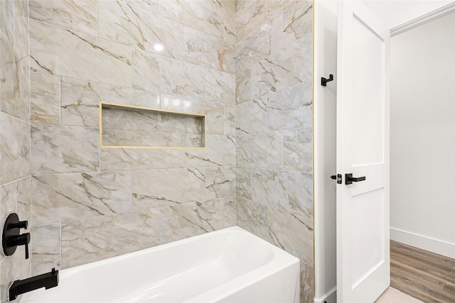 bathroom featuring hardwood / wood-style flooring and washtub / shower combination