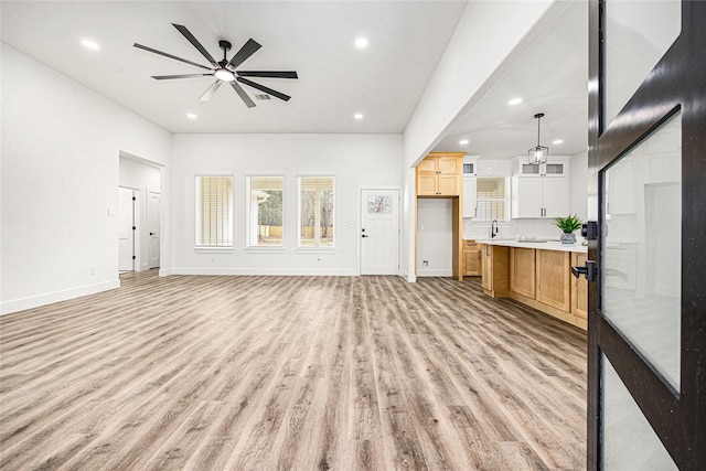 unfurnished living room featuring ceiling fan, sink, and light hardwood / wood-style floors