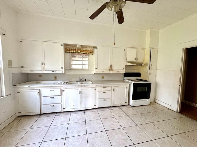 kitchen with electric stove, sink, light tile patterned floors, and white cabinets