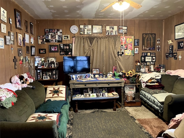 living room with ceiling fan and wooden walls