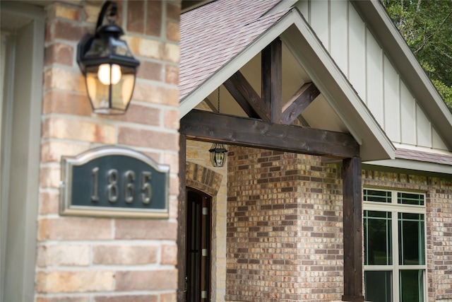 exterior details with roof with shingles, brick siding, and board and batten siding