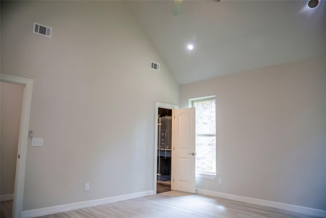 unfurnished bedroom with high vaulted ceiling, wood finished floors, visible vents, and baseboards