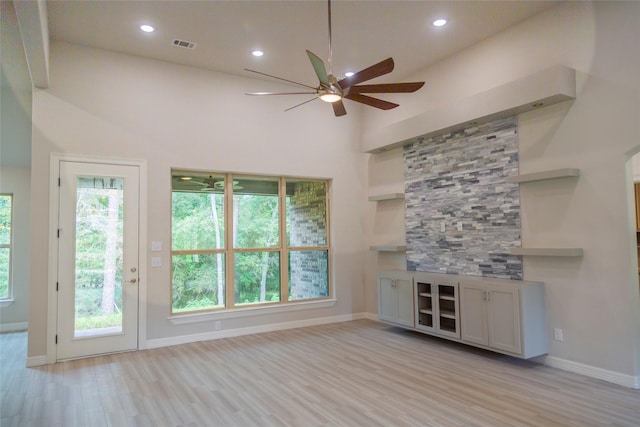 unfurnished living room with light wood-type flooring, plenty of natural light, and baseboards