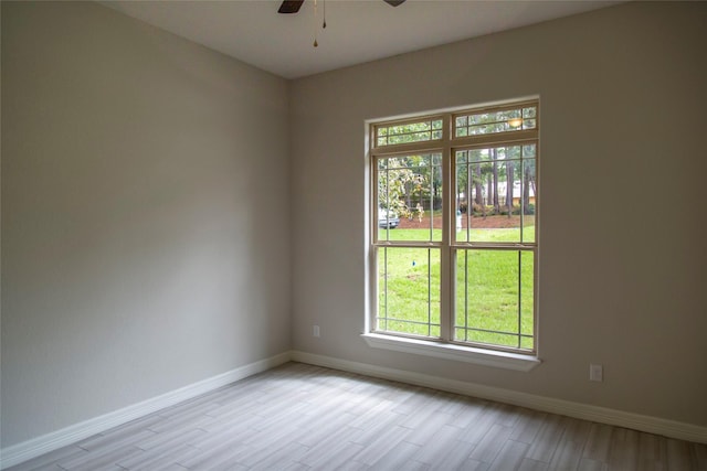 spare room with light wood-type flooring, ceiling fan, and baseboards