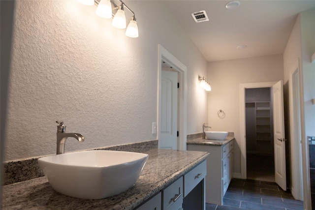 full bathroom featuring visible vents, two vanities, a sink, and tile patterned flooring