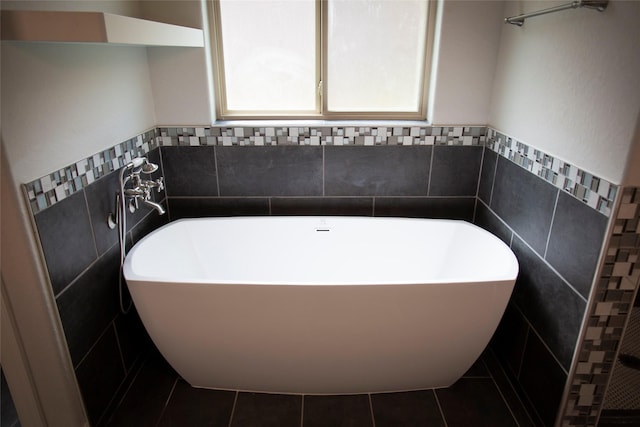 bathroom with tile patterned flooring, a soaking tub, and tile walls