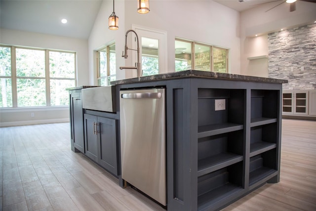 kitchen with vaulted ceiling, stainless steel dishwasher, light wood-type flooring, dark stone counters, and decorative light fixtures
