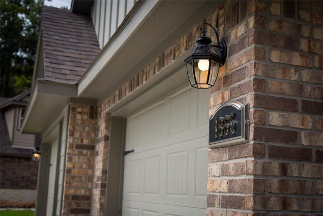 exterior details featuring a shingled roof and brick siding