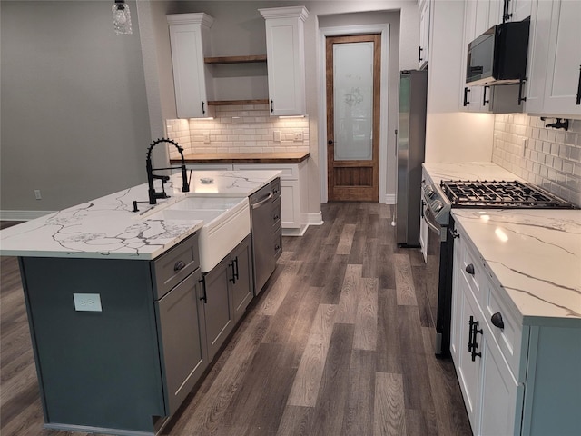 kitchen featuring white cabinets, appliances with stainless steel finishes, dark wood-style flooring, open shelves, and a sink