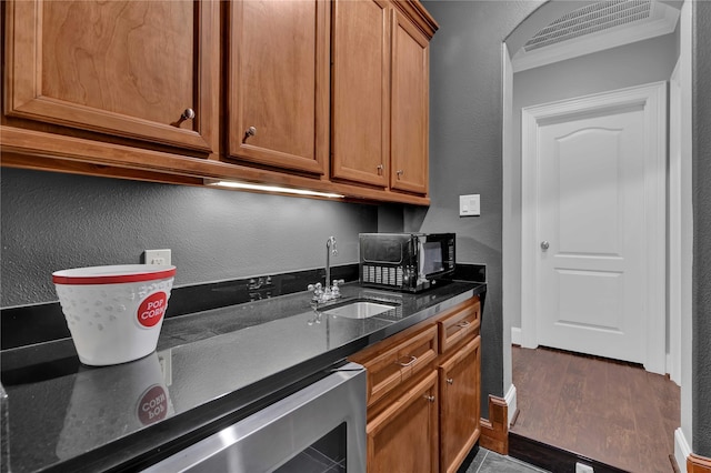 7611 Kings River Ln, Humble, TX 77346 - kitchen featuring a sink, wine cooler, a textured wall, dark wood-type flooring, and brown cabinets