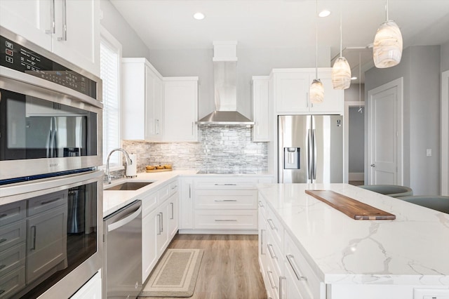 kitchen with stainless steel appliances, sink, wall chimney range hood, and white cabinets