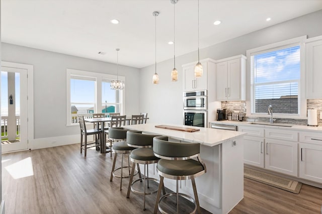 kitchen featuring stainless steel appliances, white cabinetry, a kitchen island, and a breakfast bar area