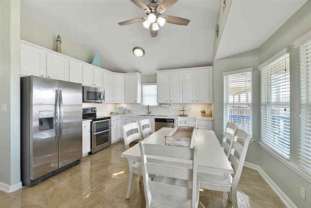 23178 Fresca St, Galveston, TX 77554 - kitchen featuring appliances with stainless steel finishes, vaulted ceiling, healthy amount of natural light, backsplash, and white cabinets