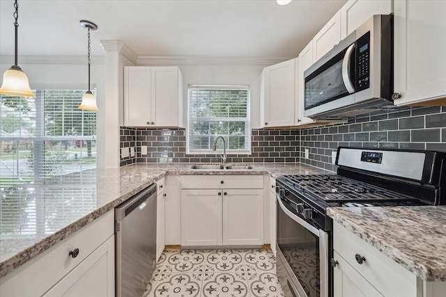 kitchen with sink, stainless steel appliances, light stone countertops, white cabinets, and decorative light fixtures