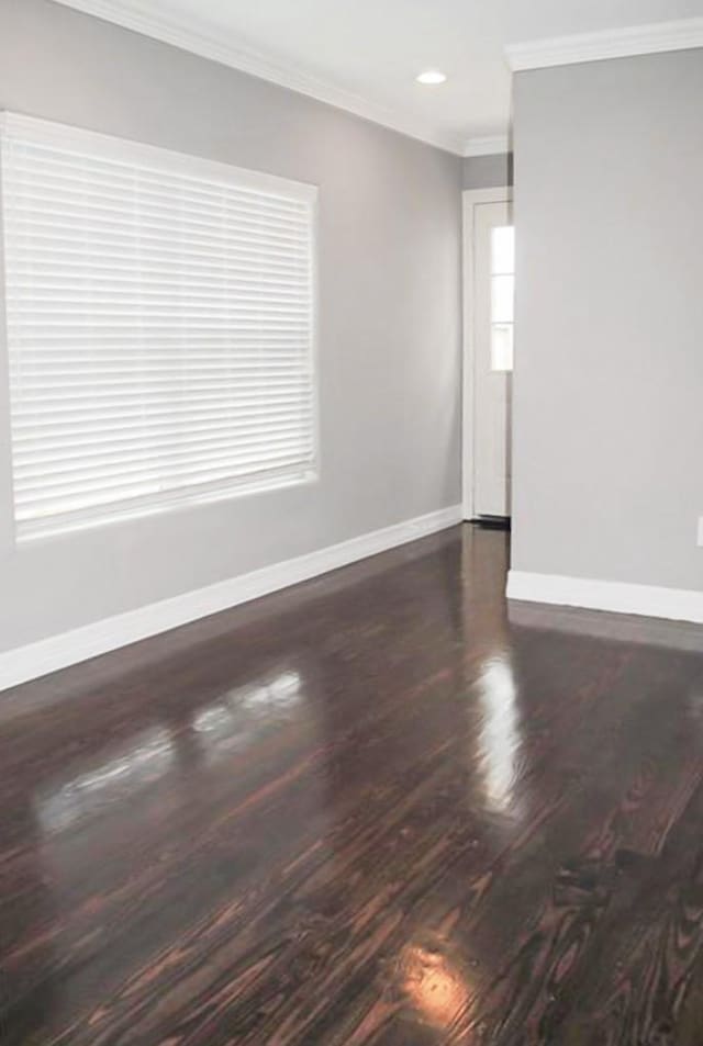 empty room with dark hardwood / wood-style flooring and crown molding