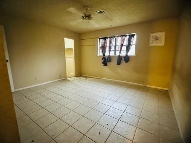 unfurnished bedroom with ceiling fan, a textured ceiling, and light tile patterned floors