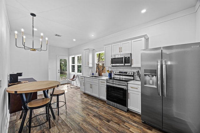 kitchen with decorative light fixtures, white cabinetry, sink, stainless steel appliances, and dark wood-type flooring