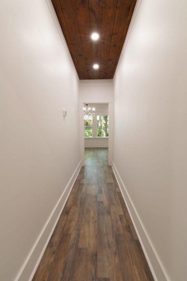 hallway featuring ornamental molding, a chandelier, wooden ceiling, and dark hardwood / wood-style flooring