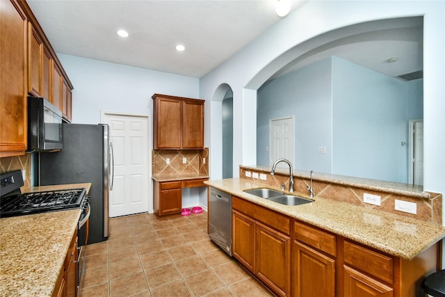 kitchen featuring sink, light stone counters, light tile patterned floors, appliances with stainless steel finishes, and backsplash