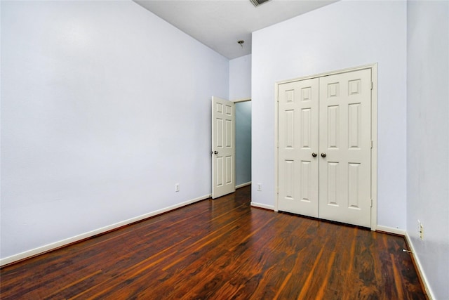 unfurnished bedroom with dark wood-type flooring and a closet