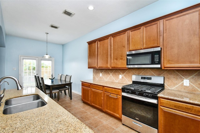 kitchen with pendant lighting, sink, backsplash, light tile patterned floors, and stainless steel appliances