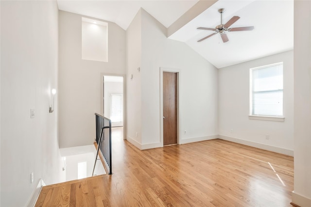 empty room with ceiling fan, high vaulted ceiling, and light hardwood / wood-style floors