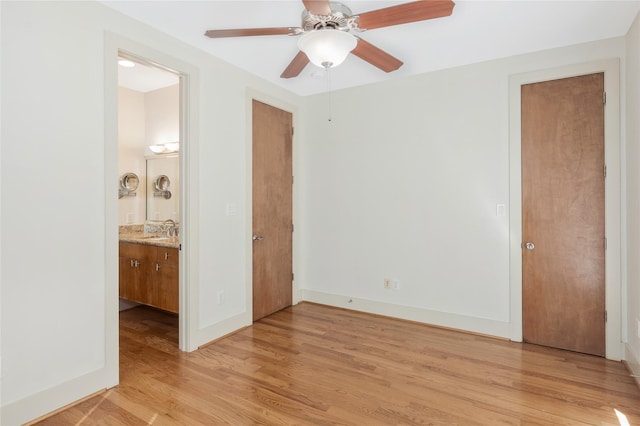 unfurnished bedroom with ceiling fan, ensuite bathroom, sink, and light wood-type flooring