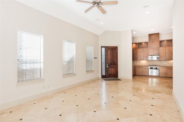 interior space featuring backsplash, vaulted ceiling, ceiling fan, and appliances with stainless steel finishes