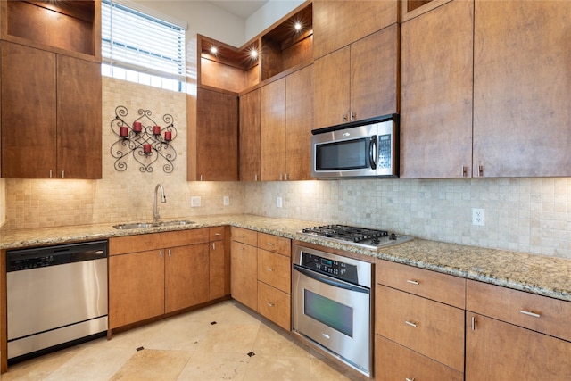 kitchen with sink, light tile patterned floors, appliances with stainless steel finishes, light stone counters, and tasteful backsplash