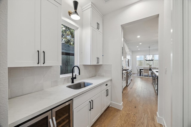 kitchen with tasteful backsplash, white cabinetry, sink, and light hardwood / wood-style floors