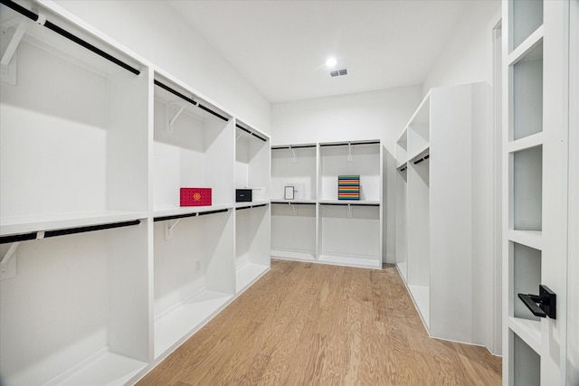 walk in closet with a barn door and light hardwood / wood-style floors